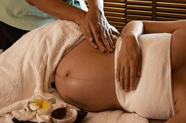 Femme enceinte se faisant masser le coté du ventre sur une position latéral